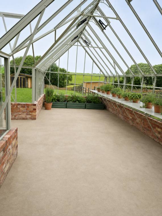 Interior of a bespoke greenhouse with brick dwarf walls, aluminium staging and raised beds